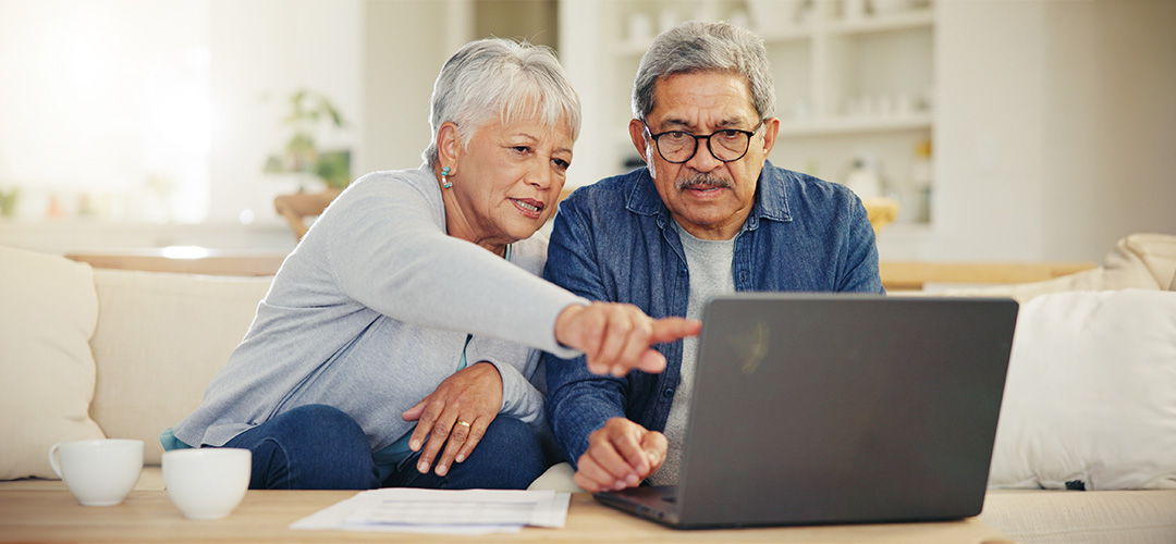 Two older people pointing at a computer benefitting from seo successes.